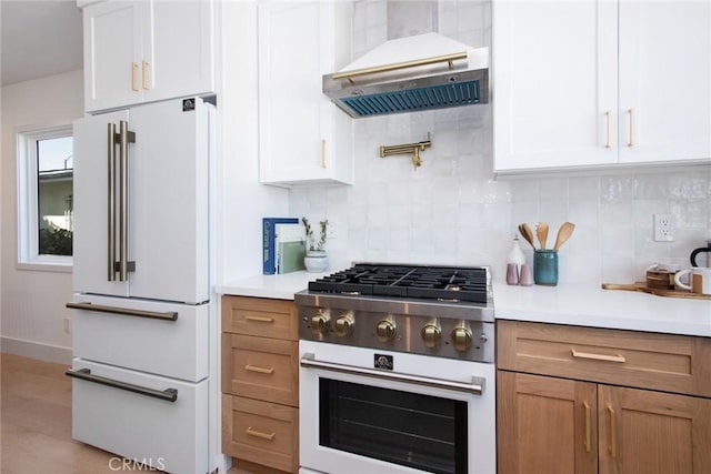 kitchen featuring white appliances, white cabinetry, under cabinet range hood, light countertops, and backsplash