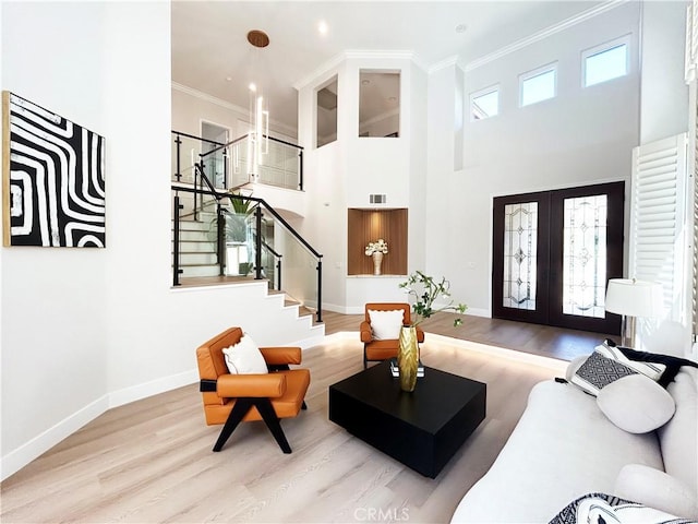 living area with french doors, wood finished floors, ornamental molding, and stairway
