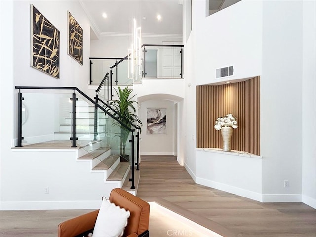 entryway with crown molding, visible vents, baseboards, and wood finished floors