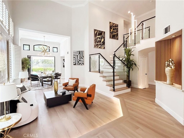 living area with baseboards, stairway, a high ceiling, light wood-style floors, and visible vents