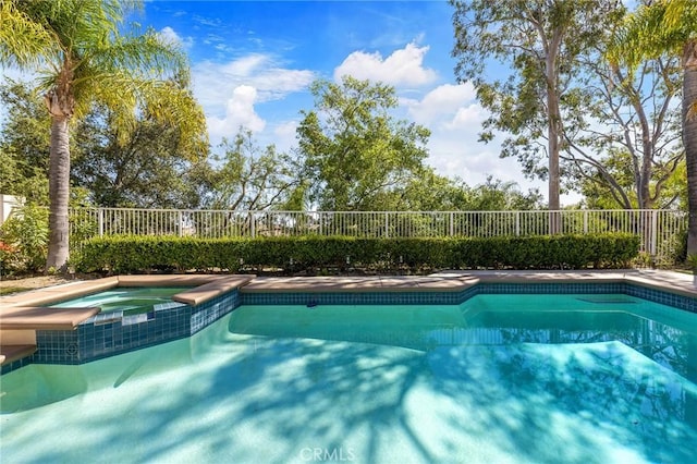 view of pool featuring fence and a pool with connected hot tub
