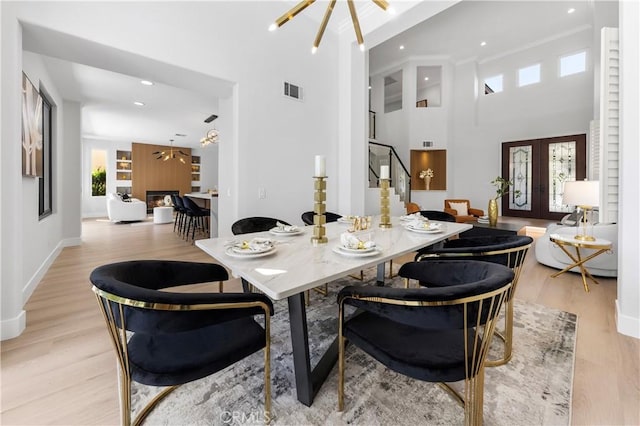 dining room featuring light wood finished floors, a notable chandelier, stairway, and a healthy amount of sunlight
