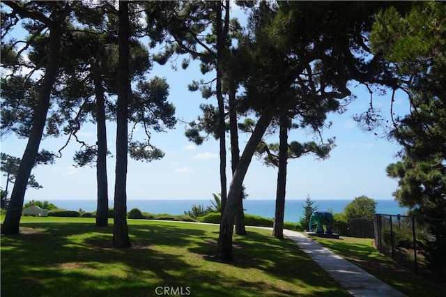 view of property's community with a yard, a water view, and fence