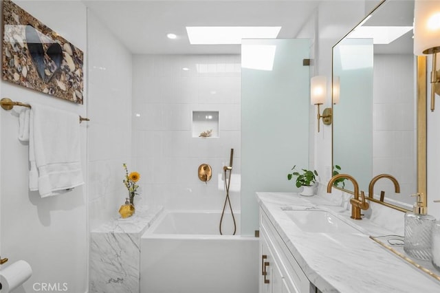 bathroom with a skylight, vanity, and a bathtub