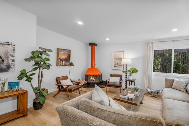 living room featuring recessed lighting, baseboards, light wood-style flooring, and a wood stove