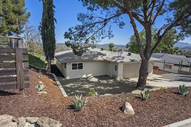 view of side of home featuring a mountain view, driveway, a garage, and stucco siding
