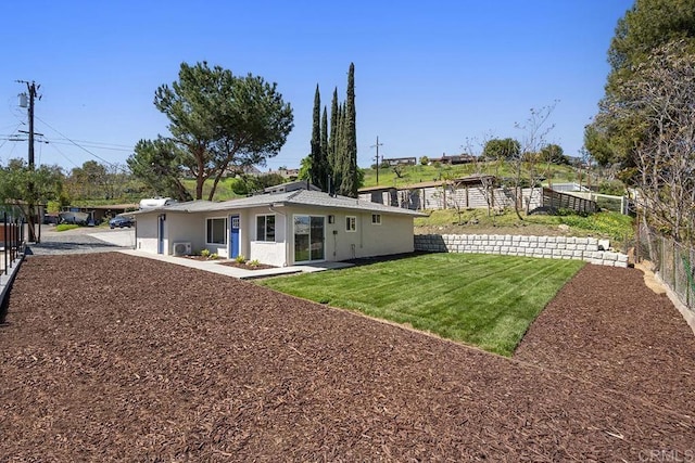 back of property with a yard, fence, and stucco siding