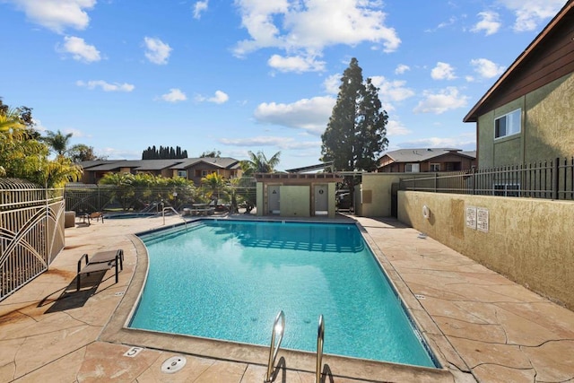 community pool with a patio, a residential view, and fence
