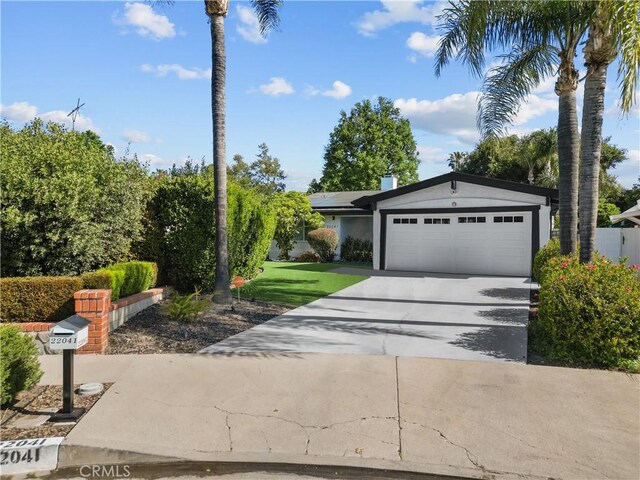 22041 Kinzie St, Chatsworth, CA 91311 - view of front facade with an attached garage, roof mounted solar panels, and driveway