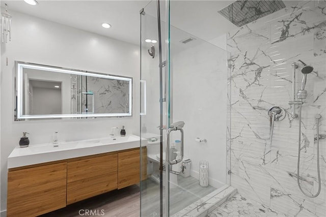 bathroom featuring a marble finish shower, toilet, recessed lighting, and vanity