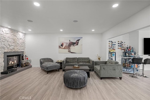 living area with recessed lighting, a stone fireplace, and wood finished floors