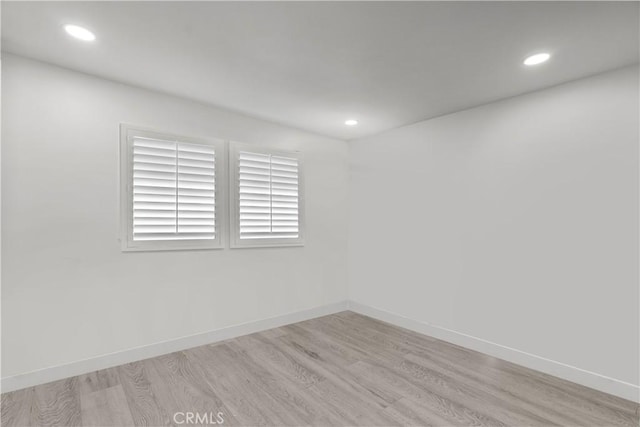 spare room featuring recessed lighting, light wood-type flooring, and baseboards