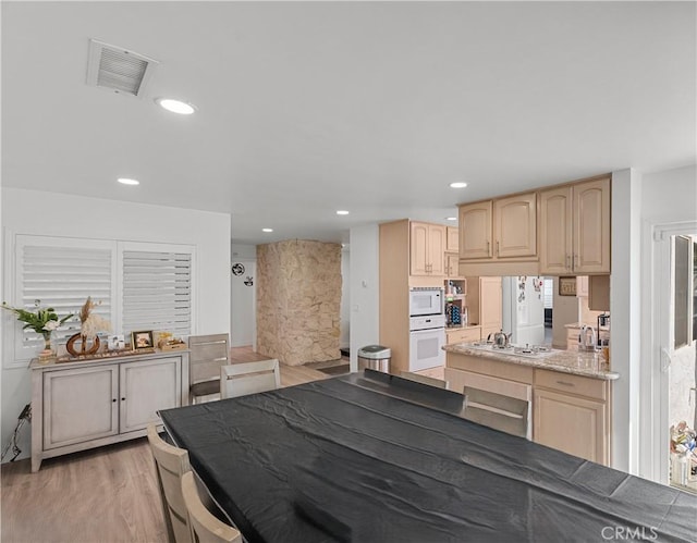 kitchen featuring light wood-style flooring, light brown cabinetry, white appliances, and visible vents
