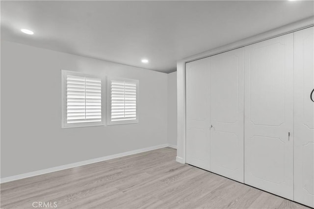 unfurnished bedroom featuring a closet, recessed lighting, light wood-type flooring, and baseboards