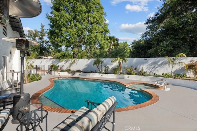 view of swimming pool featuring a fenced backyard, a pool with connected hot tub, and a patio area