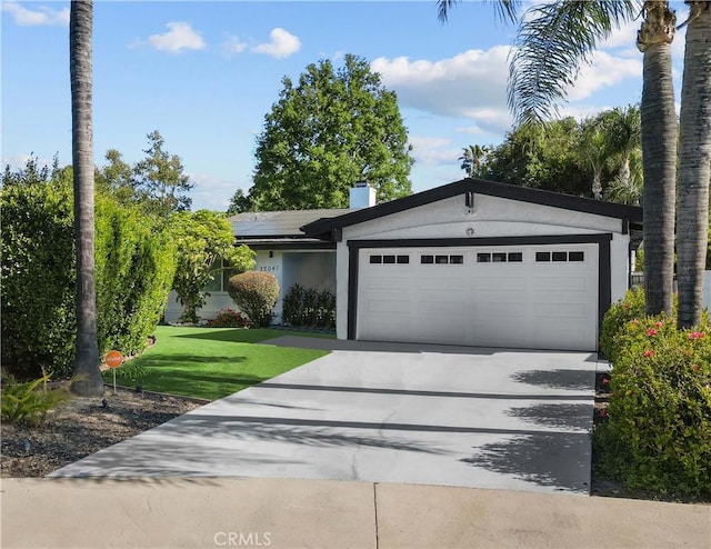 22041 Kinzie St, Chatsworth, CA 91311 - view of front facade featuring a garage, driveway, solar panels, a front lawn, and stucco siding