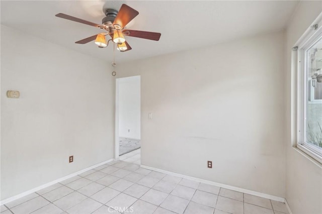 spare room featuring light tile patterned floors, ceiling fan, and baseboards
