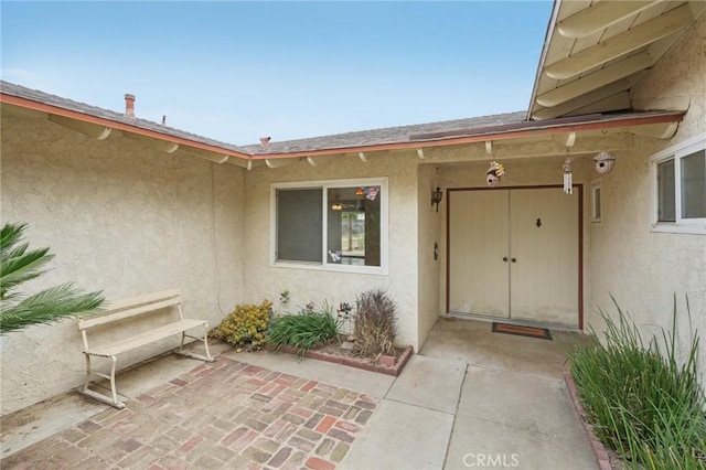 doorway to property with a patio, a garage, and stucco siding