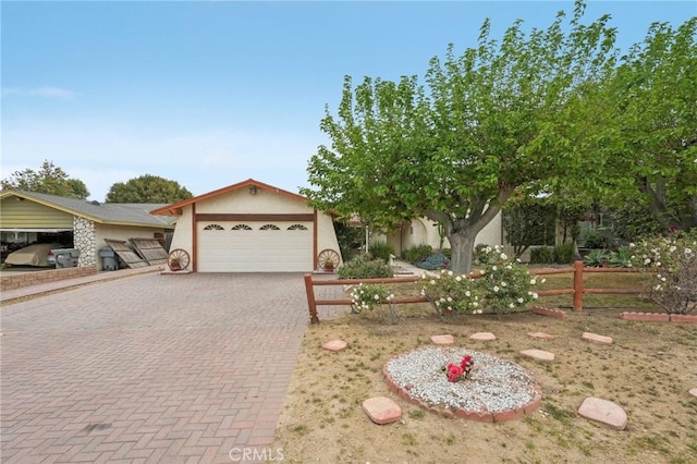 view of front of home featuring a garage, fence, stucco siding, and decorative driveway