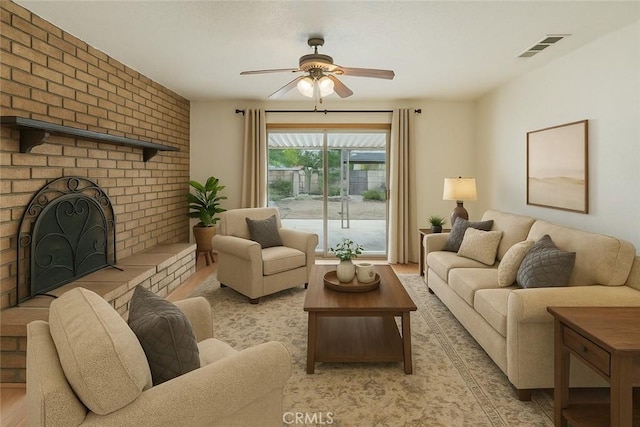 living room featuring a fireplace, visible vents, ceiling fan, and light wood-style floors