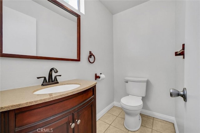 half bath featuring toilet, tile patterned floors, vanity, and baseboards