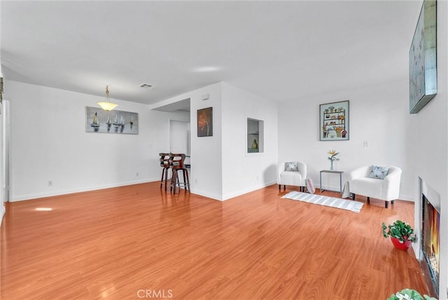 living area with light wood-style floors, baseboards, and visible vents