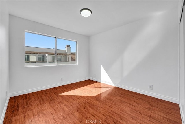 unfurnished room with baseboards and wood finished floors
