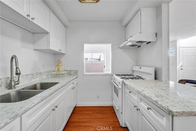 kitchen with dark wood-style floors, white cabinetry, white range with gas stovetop, under cabinet range hood, and a sink