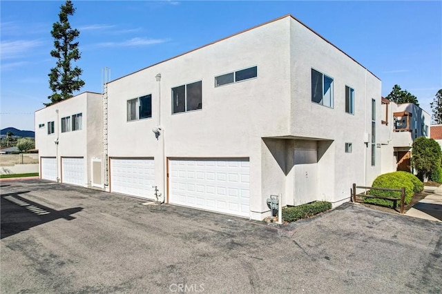 view of property exterior featuring aphalt driveway, stucco siding, and a garage