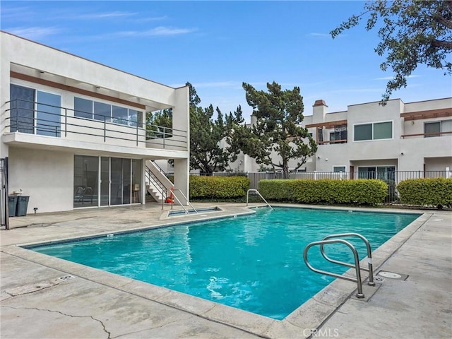 pool with a patio, fence, and stairway
