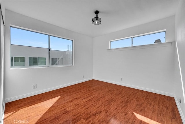 unfurnished room featuring baseboards and wood finished floors