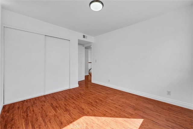 unfurnished bedroom with visible vents, baseboards, and wood finished floors