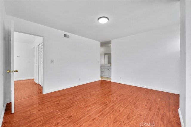 unfurnished room featuring wood finished floors, baseboards, and visible vents