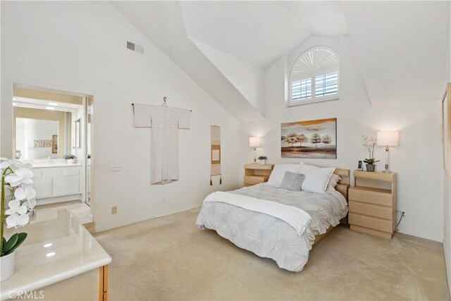 bedroom with high vaulted ceiling, light colored carpet, visible vents, and ensuite bath