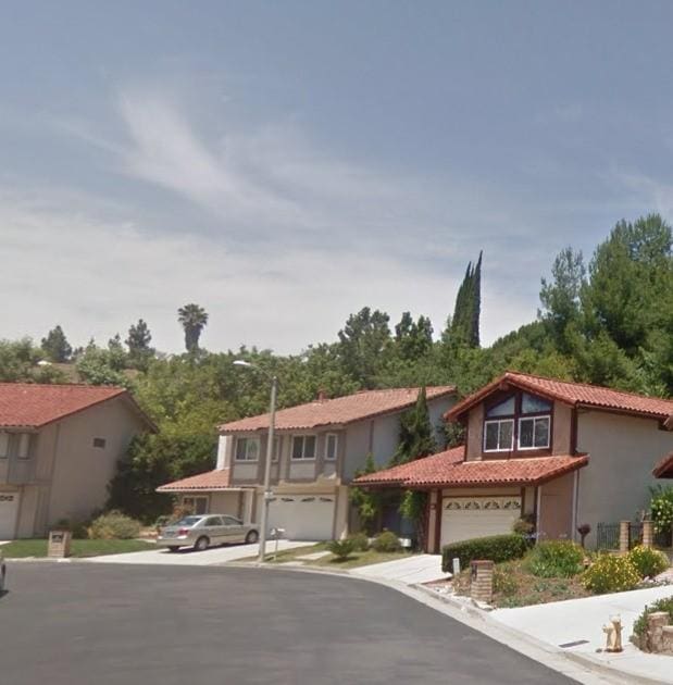 view of front of property with an attached garage, driveway, a tile roof, and stucco siding