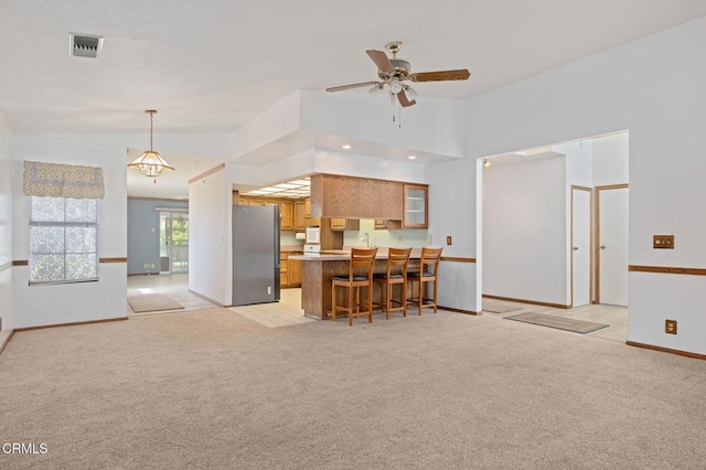 342 Colgate St, Santa Paula, CA 93060 - kitchen with visible vents, freestanding refrigerator, a kitchen breakfast bar, a peninsula, and brown cabinets