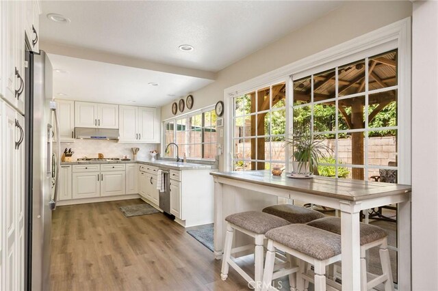 17851 Nearbank Dr, Rowland Heights, CA 91748 - kitchen featuring stainless steel appliances, backsplash, light wood-style floors, white cabinetry, and under cabinet range hood