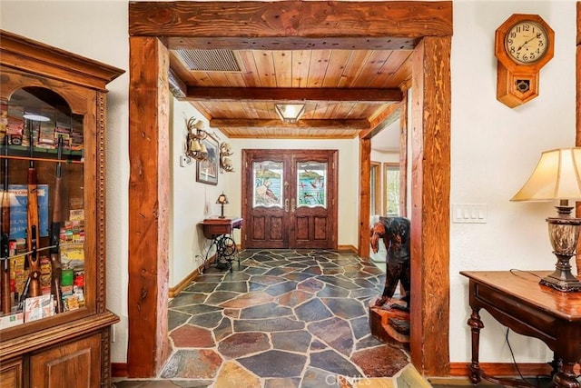 entrance foyer with beamed ceiling, visible vents, wooden ceiling, stone floors, and baseboards