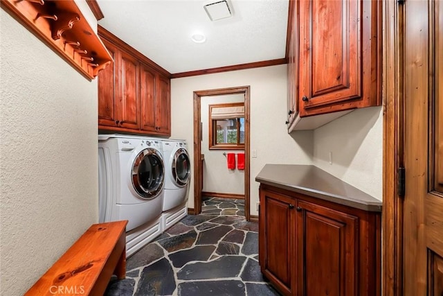 laundry room featuring crown molding, stone floors, baseboards, cabinet space, and washer and clothes dryer