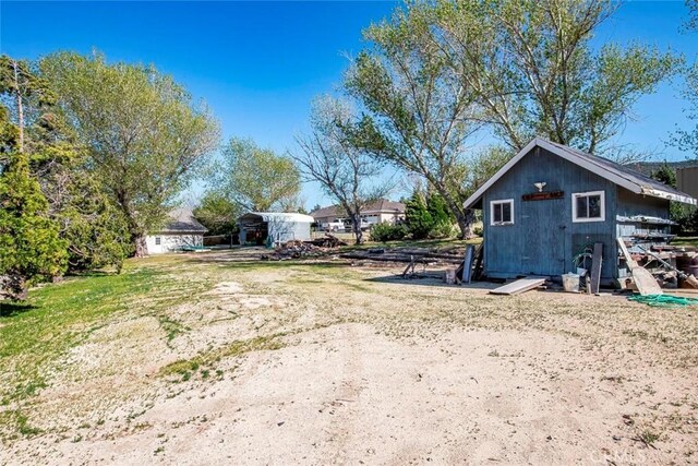 view of yard with a carport, a storage unit, and an outdoor structure