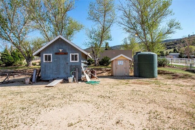 back of house with a shed, fence, and an outbuilding