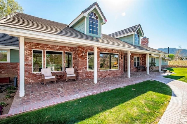 rear view of property featuring a patio, a yard, a mountain view, and brick siding