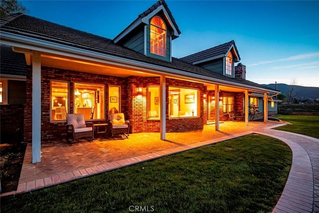 back of property with a patio area, brick siding, and a yard