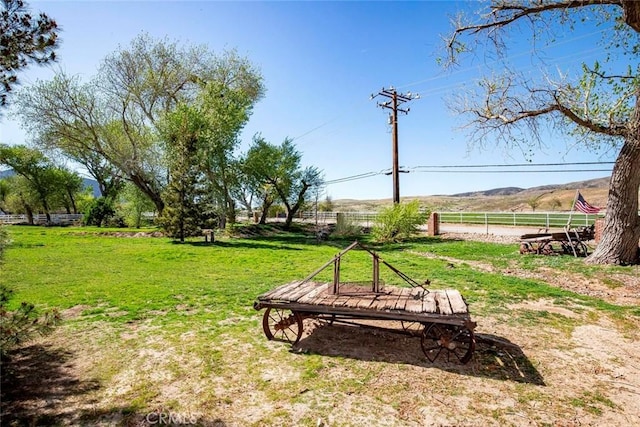 view of home's community with a yard, fence, and a rural view
