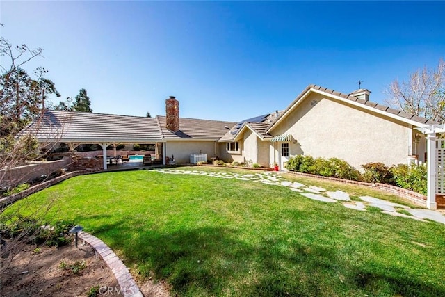 view of front of house with a tiled roof, a chimney, a patio, stucco siding, and a front lawn