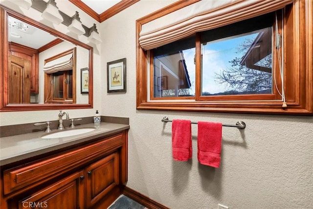 bathroom with crown molding, vanity, and a textured wall