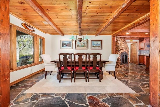 dining room with wood ceiling, beamed ceiling, a fireplace, and stone flooring