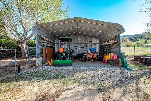 view of outbuilding featuring a carport and fence