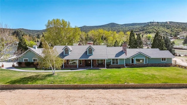 view of front of house with a mountain view, a front yard, a tile roof, and brick siding