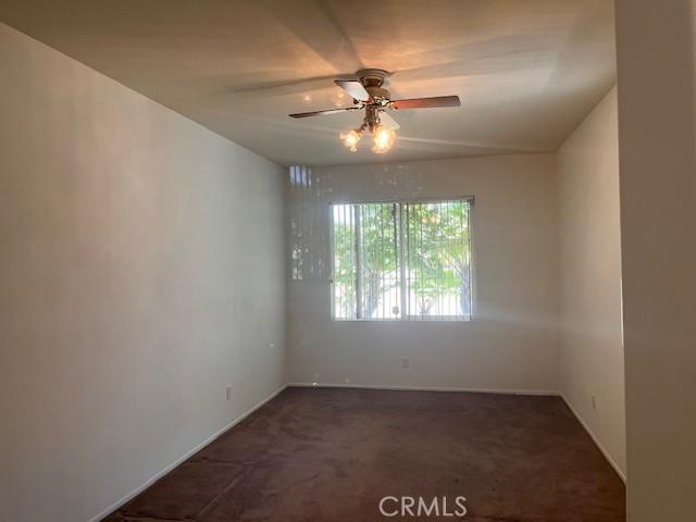 11950 Reichling Ln, Whittier, CA 90606 - empty room with dark colored carpet, a ceiling fan, and baseboards